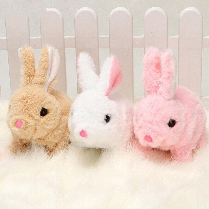 Three plush rabbit toys in beige, white, and pink against a white picket fence background.