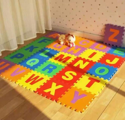 Colorful alphabet mats on a wooden floor with toys and curtains in the background.