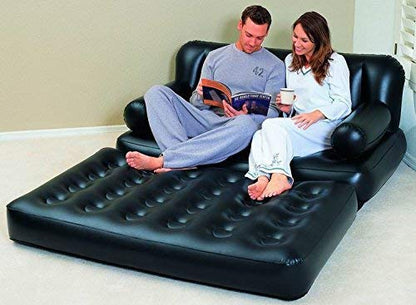 Two people sitting on an inflatable black sofa in a room.