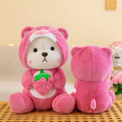 Pink teddy bear plush toy with a small green plant on a wooden surface.